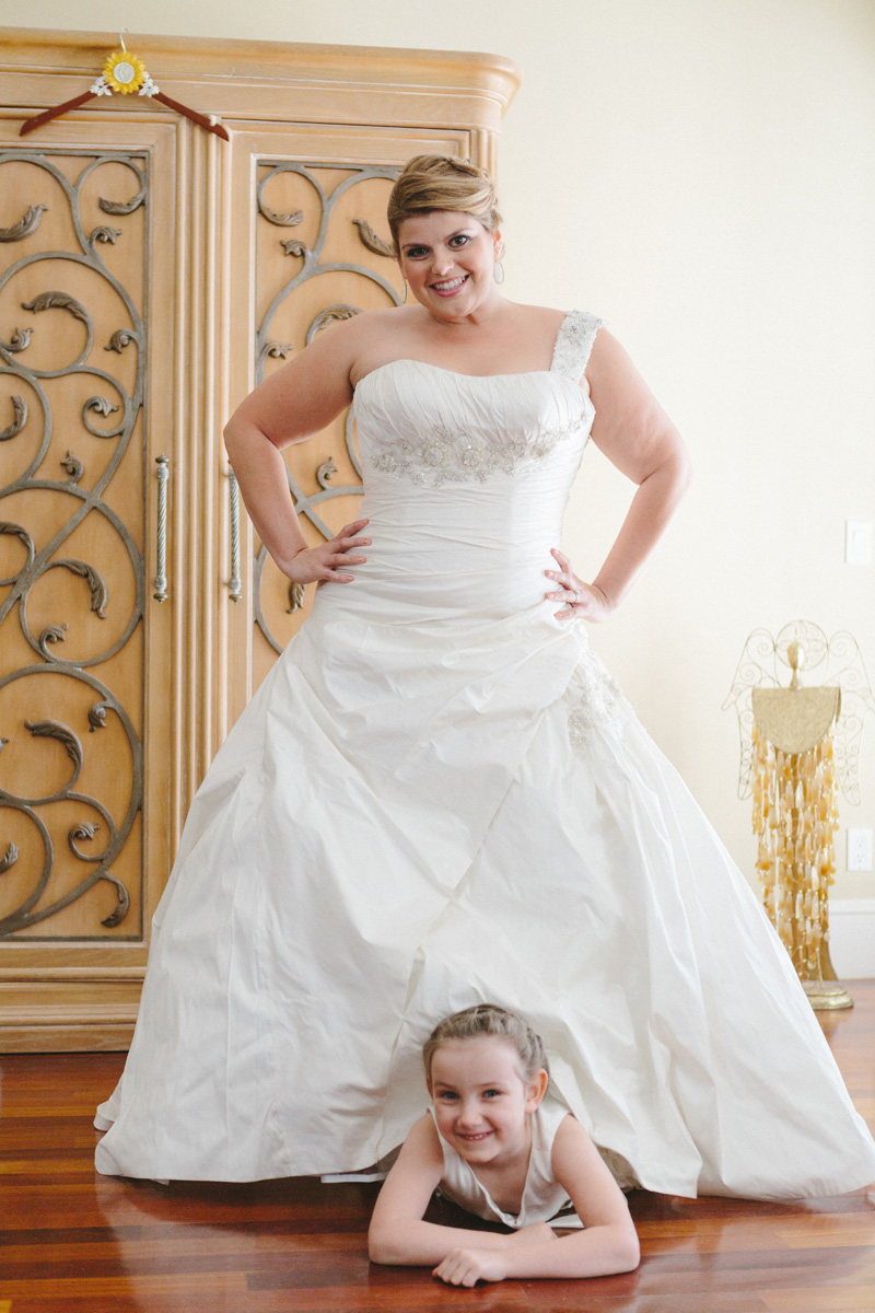 Fun Portrait of Bride with Flower Girl Peeking Out from Under Bridal Gown | The Majestic Vision Wedding Planning | Palm Beach Zoo in Palm Beach, FL | www.themajesticvision.com | Robert Madrid Photography