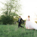 Beautiful Bride in Blush Tara Keely Gown Running Through a Field with Handsome Groom at Rustic Manor in Milwaukee, WI thumbnail