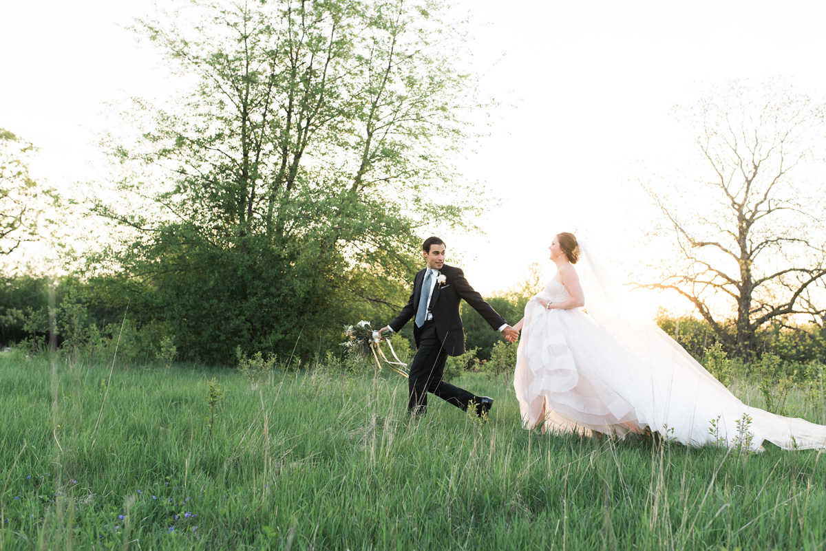 Beautiful Bride in Blush Tara Keely Gown Running Through a Field with Handsome Groom | The Majestic Vision Wedding Planning | Rustic Manor in Milwaukee, WI | www.themajesticvision.com | Elizabeth Haase Photography